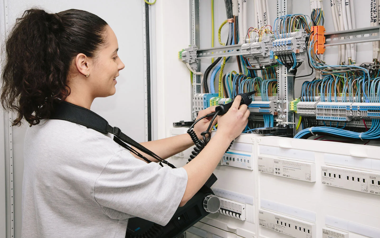 E-CHECK - Mitarbeiterin prüft im Schaltschrank mit einem Meßgerät · Winter Elektro